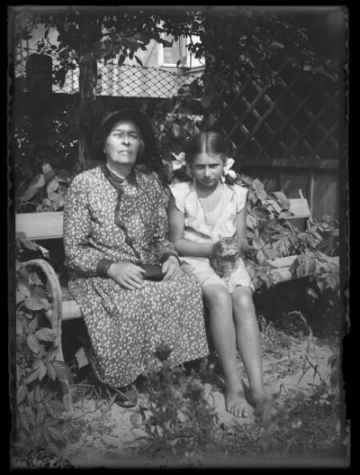 Portret starszej kobiety i Krystyny Urban siedzących na ławce w ogrodzie domu Januszów przy ul. Poniatowskiego w Rzeszowie