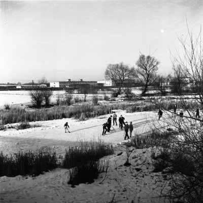 Dzieci grające w hokeja na gliniankach, tzw. stawy Czyża,  w Zwięczycy. W tle magazyny Wojewódzkiego Związku Gminnych Spółdzielni "Samopomoc Chłopska". Obecnie za magazynami ul. Przemysłowa. Widok od strony cmentarza w Zwięczycy 