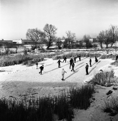 Dzieci grające w hokeja na gliniankach, tzw. stawy Czyża,  w Zwięczycy. W tle magazyny Wojewódzkiego Związku Gminnych Spółdzielni "Samopomoc Chłopska". Obecnie za magazynami ul. Przemysłowa. Widok od strony cmentarza w Zwięczycy 