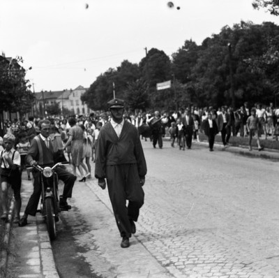 GFK-3-782 Uczestnicy Światowego Festiwalu Polonijnych Zespołów Folklorystycznych na ul. Fryderyka Szopena w Rzeszowie. W tle kamienica nr 59 . Na pierwszym planie Maniuś Drozd, jedna z najbardziej charakterystycznych postaci Rzeszowa GFK-3-782.jpg